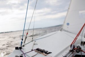 Close-up view of a sailboat deck with various ropes and hardware visible, sailing on open water near Annapolis—a perfect scene for summer self-care and refreshment under a cloudy sky. - Varuna Salon Spa in Annapolis, MD
